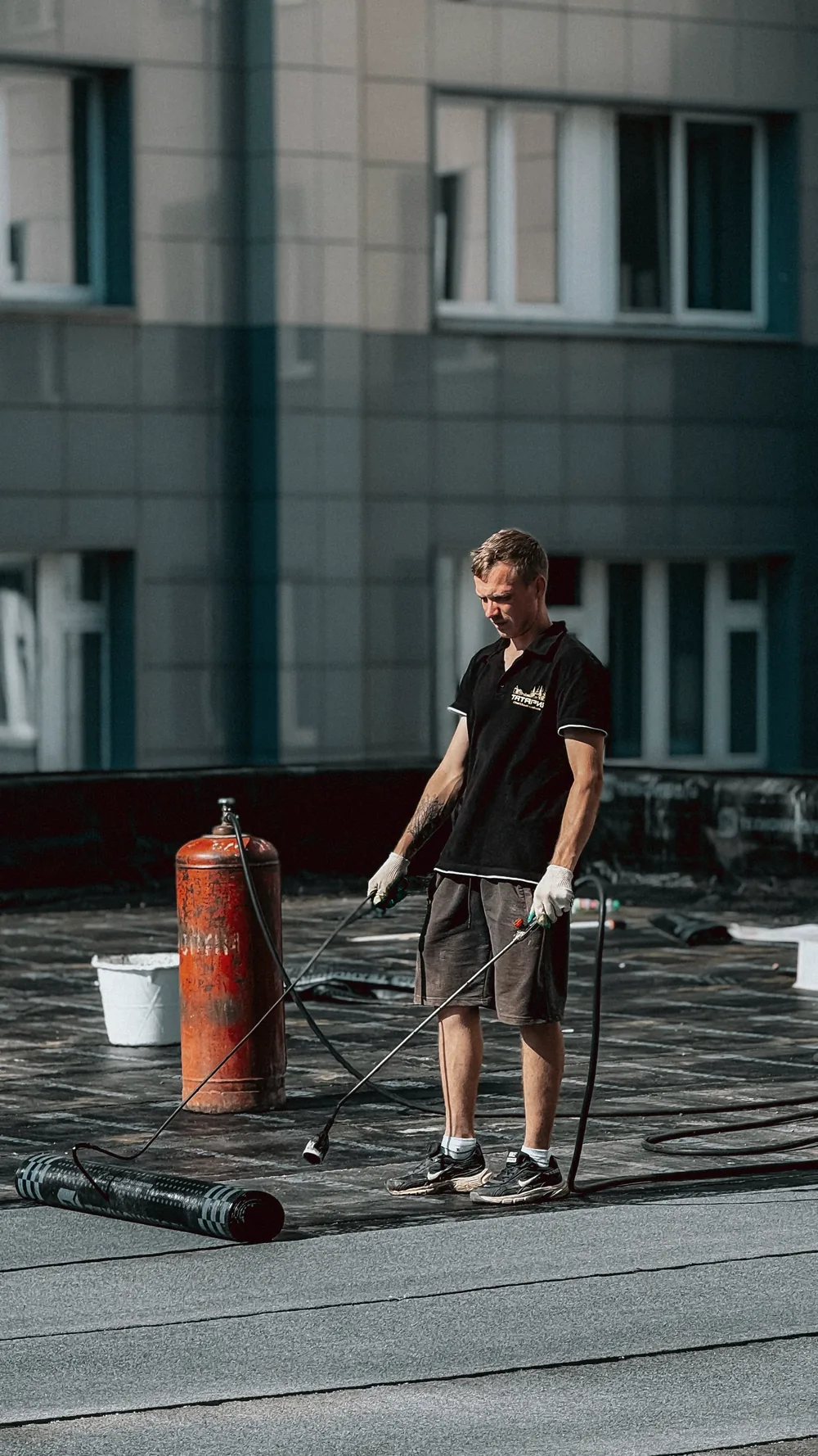 Crew installing waterproofing membrane on a flat roof